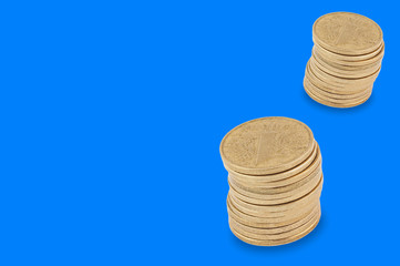 Two stacks of many yellow coins on blue background with copy space for your text. Financial concept