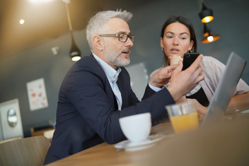 Wall Mural - Salesman showing manager proposal on cellphone during meeting