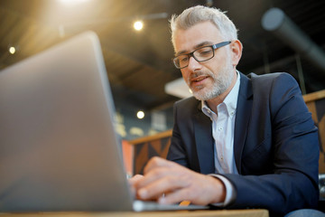 Wall Mural - Businessman working on computer at airport restaurant