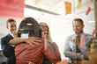 © Flamingo Images - Two businesswomen hugging after an office brainstorming session