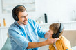 © LIGHTFIELD STUDIOS - handsome smiling father with preschooler son in headphones listening music at home