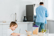 © LIGHTFIELD STUDIOS - preschooler son drawing during breakfast with father on background in kitchen