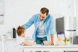 © LIGHTFIELD STUDIOS - smiling father stroking preschooler son during breakfast in kitchen