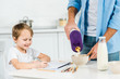 © LIGHTFIELD STUDIOS - father pouring cereal in bowl while smiling preschooler son drawing during breakfast in morning