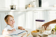 © LIGHTFIELD STUDIOS - happy preschooler son drawing while father pouring milk in bowl during breakfast in kitchen
