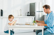 © LIGHTFIELD STUDIOS - father and preschooler son eating cereal during breakfast in kitchen