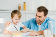 © LIGHTFIELD STUDIOS - smiling father and preschooler son drawing during breakfast in kitchen