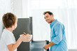 © LIGHTFIELD STUDIOS - selective focus of smiling father in kitchen with boy holding bowl of cereal on foreground