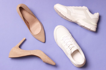  white sneakers and high heel shoes on a colored background top view. Women's shoes. Classic and sport shoes.