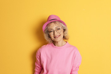 Wall Mural - Portrait of mature woman in hipster outfit on color background