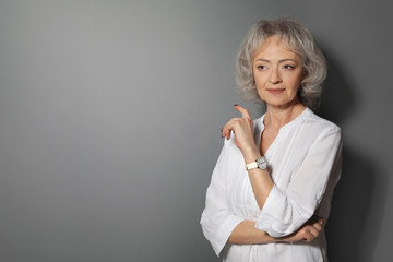 Wall Mural - Portrait of mature woman on grey background. Space for text