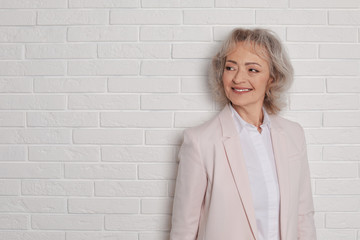 Wall Mural - Portrait of mature woman near brick wall. Space for text