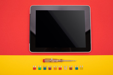 Set of electrical tool and black tablet on colorful background