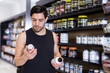 © JackF - Serious young muscular man choosing  sport dietary supplements