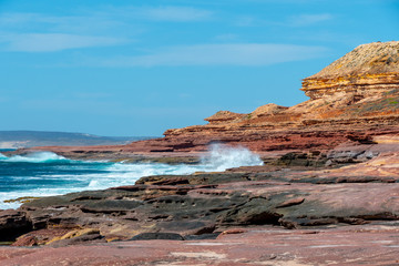 Wall Mural - Waves hitting rock coast with different colors from red to yellow in the Kalbarri National Park Australia