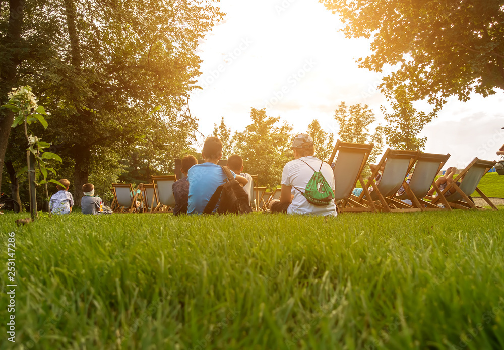 People sit in the park at the summer cinema. - obrazy, fototapety, plakaty 