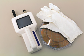 Silicon Wafer in plastic holder box on a table with particle counter near.