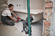 © Kadmy - bathtube installation. plumber installing and mounting bath with laser level