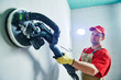 © Kadmy - Worker smoothig and finishing wall with long reach sander before painting