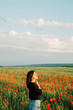 © vdeineka - oriental girl is standing in a field of poppies.young girl enjoys a summer sunset. Copy space for text