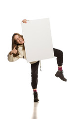 Wall Mural - Young model in hoodie holding an empty advertising board on white background