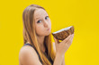 Young woman doing oil pulling over yellow background
