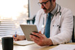 © Jacob Lund - Doctor with digital tablet writing notes at his desk