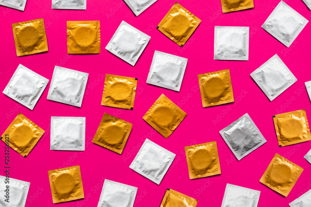 Condoms in pink background, top view. Large amount of condoms, shot from above - safe sex and contraception concept - obrazy, fototapety, plakaty 