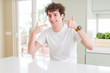 © Krakenimages.com - Young handsome man wearing white t-shirt at home smiling confident showing and pointing with fingers teeth and mouth. Health concept.