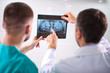 © frimufilms - Two caucasian male dentists analyzing x-ray