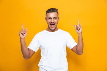 Sticker - Happy excited man posing isolated over yellow wall background pointing.