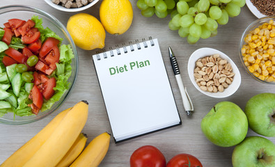 notebook with a diet plan with fresh vegetables and fruits on the table