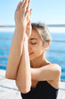 © vitaliymateha - Portrait of a young sporty attractive woman practicing yoga, doing Garudasana arms exercise at the beach with blue sea background. Feeling so comfortable and relax. Morning meditation. Healthy Concept