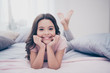 © deagreez - Close up photo cute sweet beautiful she her little girl crossed legs lying down pillow hands arms hold head homey sunday wear home t-shirt pants comfortable apartments flat bright light colored room