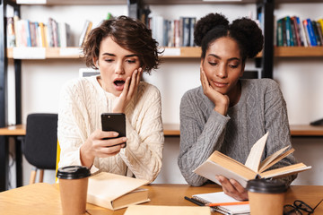 Two cheerful young girls students studying