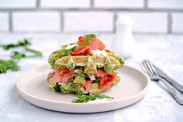 Light dinner, lunch or lunch, savory spinach snack waffles with salted salmon and cream cheese on a ceramic plate