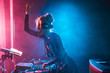 happy dj girl with blonde hair using dj mixer in nightclub with smoke