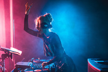 Happy Dj Girl With Blonde Hair Using Dj Mixer In Nightclub With Smoke