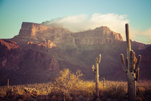 The Superstition Mountains Of Arizona In Morning Light With Saguaro Cactus And Clouds.