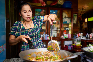 thai woman cooking traditional red curry in wok