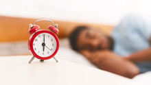 Man Sleeping With Alarm Clock On Foreground