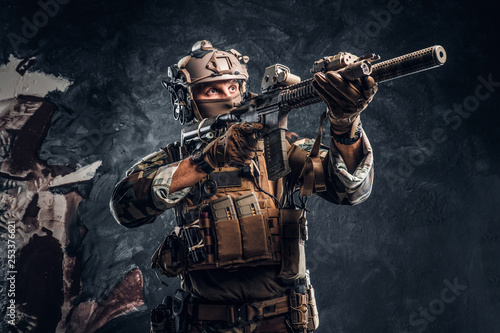 Cuadros en Lienzo Elite unit, special forces soldier in camouflage uniform holding an assault rifle with a laser sight and aims at the target