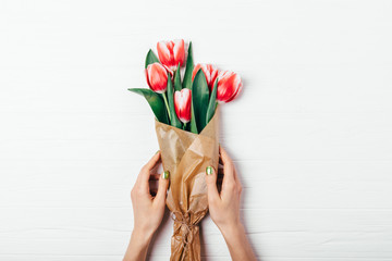 Woman's hands with green manicure holding bouquet of red tulip flowers