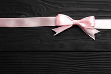 Beautiful Pink Bow And Ribbon On Black Wooden Background. Congratulations Concept.