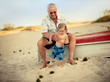 © Erickson Stock - Grandfather holding grandson on beach