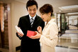 © Erickson Stock - Young adult businessman giving a gift to his girlfriend in a lobby.