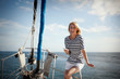 © Erickson Stock - Portrait of smiling mid-adult woman standing on boat deck, holding cell phone.