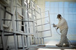 © Erickson Stock - Mid adult man in protective clothing spray painting window frames inside a garage.