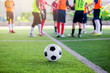 © Koonsiri - football on green artificial turf with blurry soccer players standing