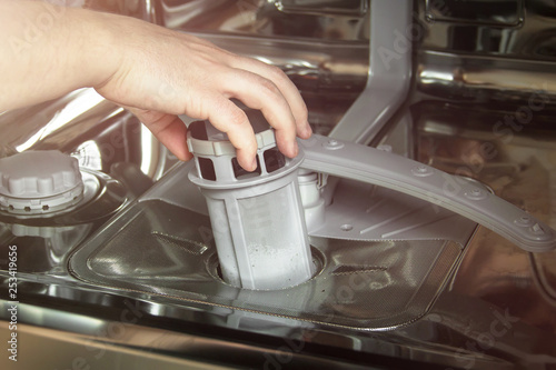 Где находится фильтр в посудомойке man cleans the filter in the dishwasher. Maintenance of home appliances. фотогра